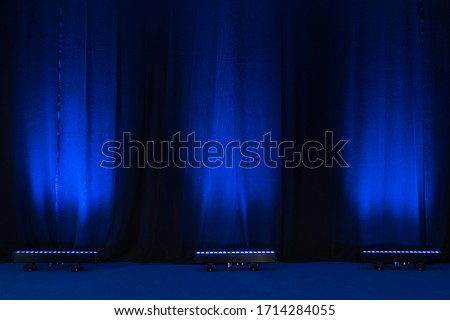 Velvet blue theatre curtains lit by three led uplights  Royalty-Free Stock Photo #1714284055