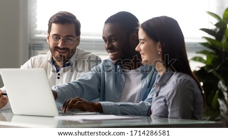Happy diverse businessman and businesswoman laughing looking at laptop screen. African american man, woman and colleague smiling and have fun free time. Teamwork at workplace concept. Royalty-Free Stock Photo #1714286581