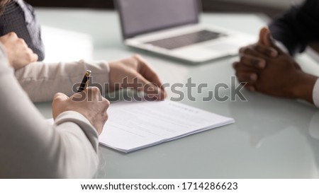 Close up diverse hands sign up document at meeting. Client making deal with professional manager at negotiate in office. Successful man concludes agreement with lawyer.