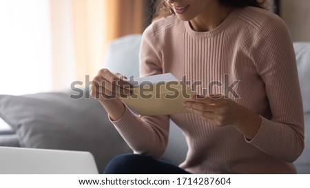 Close up smiling young woman holding envelope with paper letter or invitation inside, waiting for good news notification, banking loan approval. Happy student reading university college admission. Royalty-Free Stock Photo #1714287604