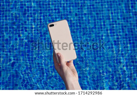 Smart phone in hand on the background of the swimming pool in a matte transparent case back view. iPhone 8 plus case mock up