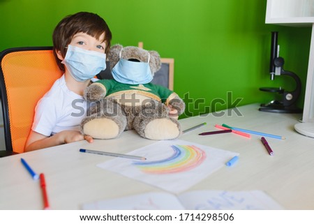 Kid in mask painting rainbow at home during coronavirus pandemic concept. Let's all be well. Stay at home Social media campaign. Children Chase the rainbow