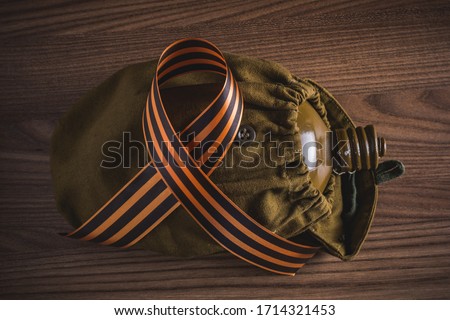 Military flask on a wooden background. George ribbon. 9 May Victory Day holiday. 9 May concept. Selective focus.