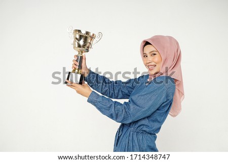 Happy Muslim girl with winning trophy over white background.                                
