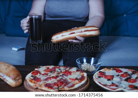 Nerve food, addiction, eating disorders, bulimia. Overweight woman sit on the coach with big amount of junk food Royalty-Free Stock Photo #1714375456