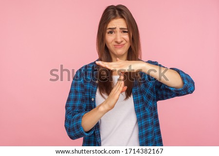 I need more time, enough limits! Portrait of displeased girl in checkered shirt showing time out hand gesture, looking imploringly, worried about deadline. studio shot isolated on pink background Royalty-Free Stock Photo #1714382167