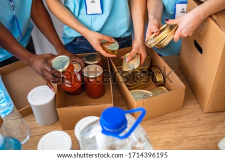 Small mixed race group of people working in charitable foundation. Generous people helping to poor people. People Donating Food To Charity Food Bank Collection In Community Center Royalty-Free Stock Photo #1714396195