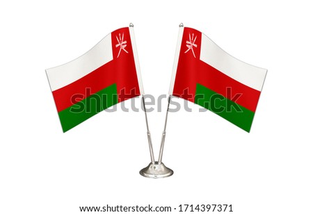 Oman table flag isolated on white ground. Two flag poles with flags and Oman flag on the table.