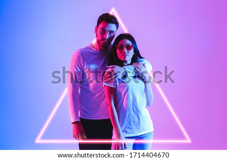 European man hugs asian woman in luminous triangle in neon