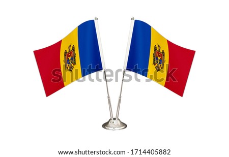 Moldova table flag isolated on white ground. Two flag poles with flags and Moldova flag on the table.