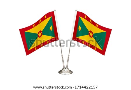 Grenada table flag isolated on white ground. Two flag poles with flags and Grenada flag on the table.