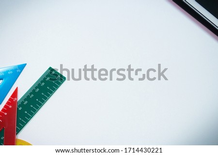 Tablet, colourful rulers and protractor on white table. There is copy space in centre in image.