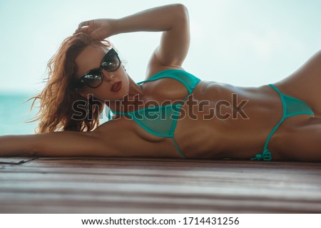 Young fit beautiful bikini female model pose in the mini micro bikini showing her beautiful body