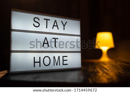 A sign with the text stay at home, a person working at a computer in a light on the background. COVID-19 Coronavirus STAY HOME SAVE LIVES viral social media message sign with text for social Royalty-Free Stock Photo #1714459672