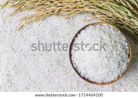 Wooden bowl with rice on rice and rice ears background with copy space for your text, top view. Natural food high in protein Royalty-Free Stock Photo #1714464100