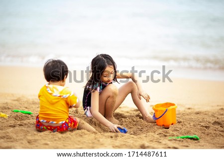 little girl and boy playing sand on the beach
