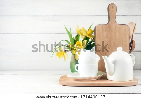 Kitchen wide banner concept. Kitchen background for mockup with spoon, teapot, cups, bowls, flowers on wooden table .