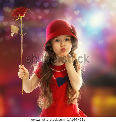 People, happiness concept. Happy little girl with rose in red clothes sends kiss her hand
