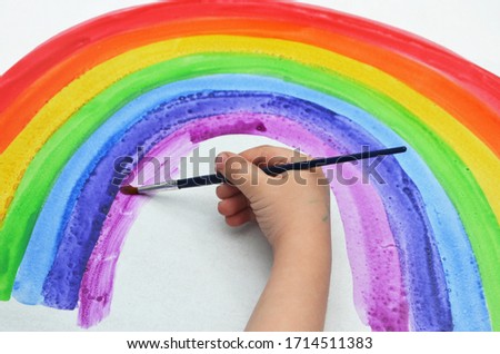 "Chase The Rainbow" Challenge. 
hand of a small child with a brush paints a rainbow in watercolor. Coronavirus Patient Support