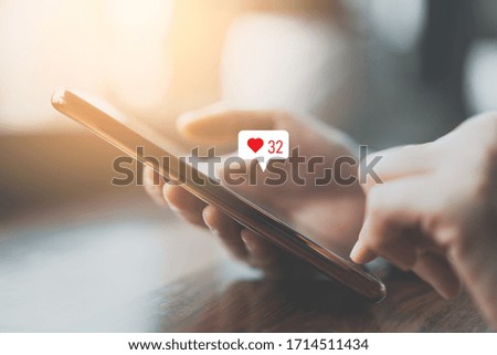Woman hand using smartphone with heart icon at coffee shop background. Technology business and social lifestyle concept. Vintage tone filter effect color style.
