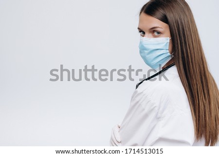 Confident woman doctor wearing medical mask standing isolated. female portrait