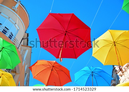Close up of colorful umbrellas against the blue sky between two houses. Street design. Shooting from below. The diagonal composition. Bright holiday picture. Background, wallpaper.
