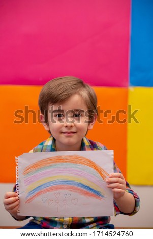 Kid painting rainbow during Covid-19 quarantine at home. 