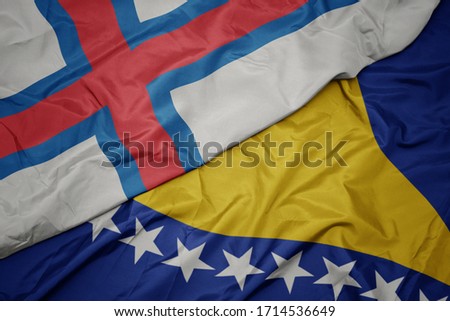 waving colorful flag of bosnia and herzegovina and national flag of faroe islands. macro