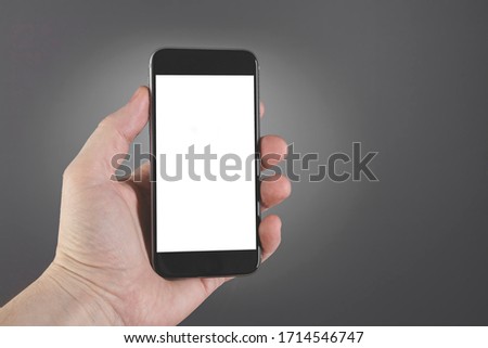 Man hand hold smartphone on gray background. Copy space