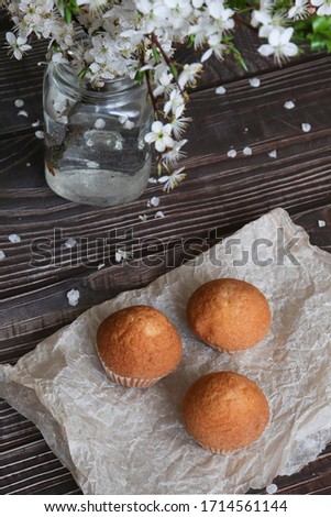  Cupcakes on paper and on a wooden brown background, composition with white flowers.View from above.