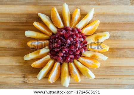 Sliced apples, Sliced bananas; mandarin slices and peeled pomegranate on a blue background.