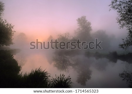 A pink sky during sunrise on the misty River Wey, Surrey, England Royalty-Free Stock Photo #1714565323