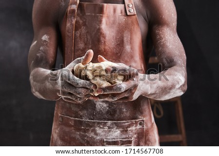Dark skin baker man kneads Dough in the kitchen. Pastry chef prepares yeast dough for pizza pasta. 
