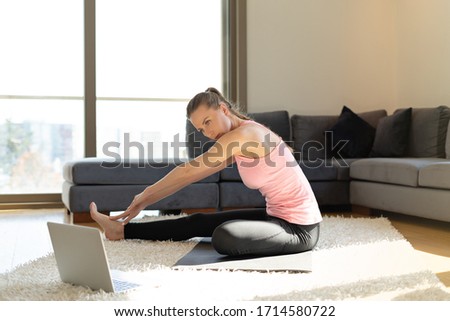Online sport fitness yoga training. young woman and doing exercises on yoga mat opposite computer with online master class. training at home.
