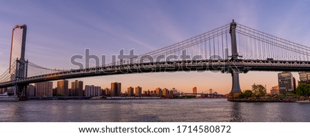 Magical evening sunset view of the Manhattan bridge from the Brooklyn park with a lower Manhattan view on the other side of the Hudson river.