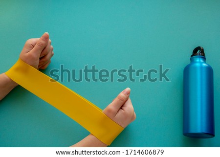 
female hands doing exercise with fitness rubber bands on a blue background.home gym concept
