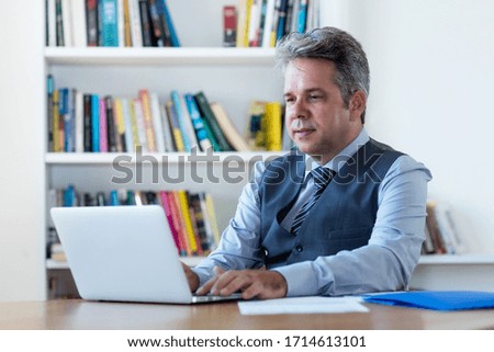 Concentrated mature businessman in quarantine at computer at desk at home office