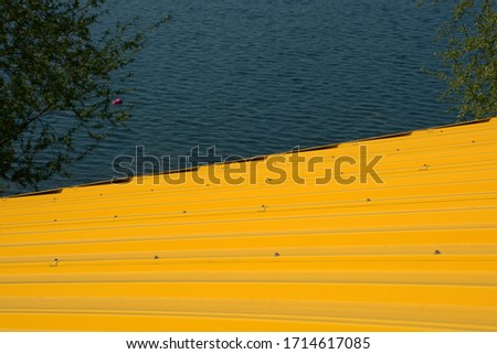 bright-yellow corrugated iron roof of a hut near the lake