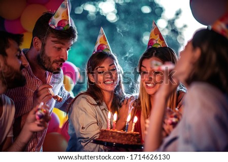 Group of friends celebrating birthday together outdoors.Concept of celebrating and happiness.