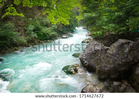 A magnificent green wild mountain landscape with a picturesque cascading blue river.