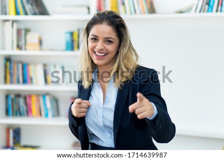 Laughing blond businesswoman in quarantine recommending stay at home and looking at camera