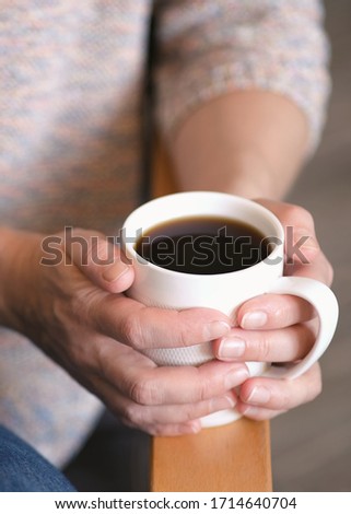 Greeting card with high resolution. Photo for printing. Blurred background. The girl was sitting comfortably in a chair, holding a Cup of coffee. Tinted photo.
