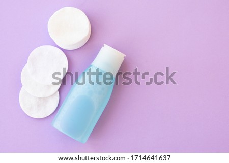 Top view of facial toner and round cotton pads on purple background with copy space. Blue liquid tonic or make up remover for face care Royalty-Free Stock Photo #1714641637