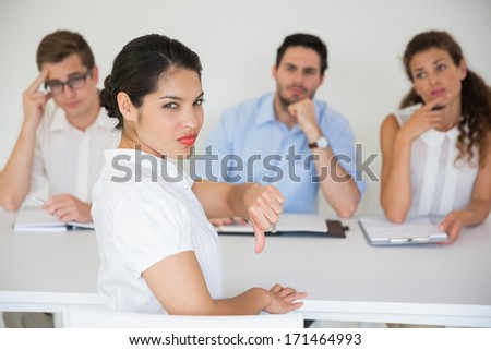 Portrait of female candidate gesturing thumbs down with interviewers in background Royalty-Free Stock Photo #171464993