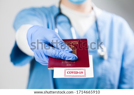 NHS doctor holding passport with COVID-19 sign stamped onto white paper,immunity passport risk-free certificate concept,recovered Coronavirus COVID19 patients being issued proof of convalescence,UK ID Royalty-Free Stock Photo #1714665910