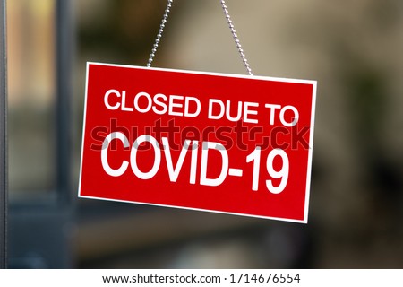Temporarily closed sign for Covid-19 in small business activity. Information notice sign about quarantine measures. Close up on a red closed placard in the window of a shop for coronavirus.