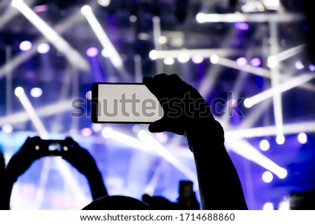 Collecting digital memory is loosing capability of being present, silhouette of a man hand shooting the concert with his smart phone