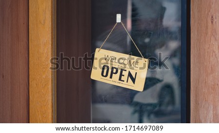 Wooden OPEN sign hanging inside a shop door.                              