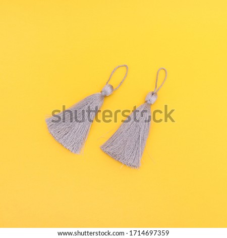 A pair of ethnic grey fringes for fashion and accessory design, top view on yellow background