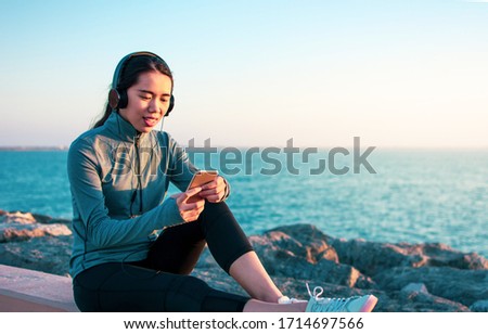Asian girl enjoying music by the seaside Royalty-Free Stock Photo #1714697566
